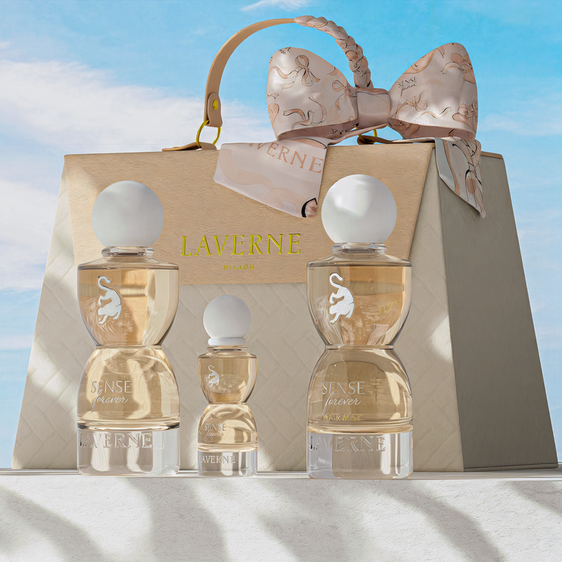 Laverne Sense Forever perfume trio displayed in front of a beige gift bag with a silk bow against a blue sky.