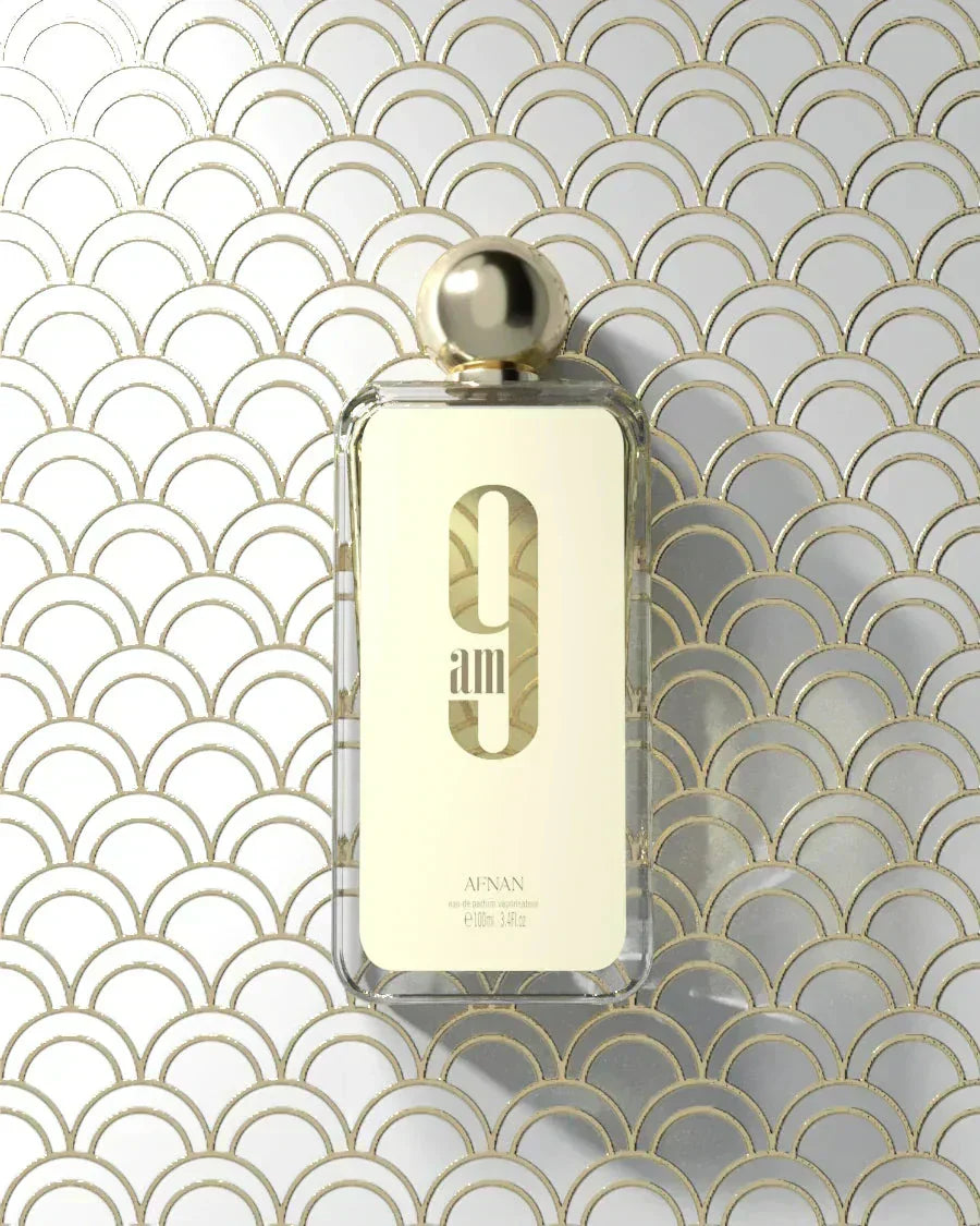 The image displays a transparent perfume bottle with a golden cap, set against a geometric patterned background composed of overlapping arches in gold and white.  Below this is the brand name "AFNAN" in smaller, capitalized letters. The product specifications "eau de parfum vaporisateur," "100ml," and "3.4fl.oz" are listed at the bottom of the label. The overall aesthetic is luxurious and modern.