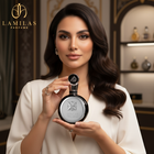 Elegant woman holds a round black Fakhar Lattafa perfume bottle with a silver label in a luxury store setting.