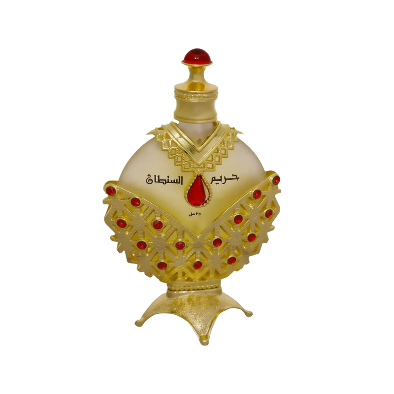 The image displays an opulent perfume bottle with a white background. The body of the bottle is a pale, translucent yellow, topped with a bright red cap resembling a gemstone.