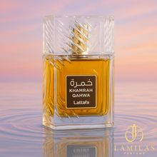 Lattafa Khamrah Qahwa perfume bottle on rippled water with soft pastel sky background.