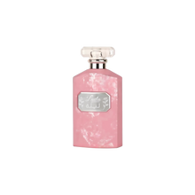 The image shows a flat, rectangular-shaped perfume bottle with a textured pink surface that has a marbled or distressed look. The bottle has a clear, rectangular glass cap. On the front, there's a label with the name "Laila" in stylized script, along with Arabic script beneath it. The label is framed by a silver border, giving the bottle a feminine and elegant appearance.