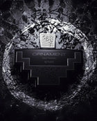 The image displays a monochrome perfume bottle with a distinctive geometric shape set against a textured, dark background resembling cracked stone or dried earth. The bottle is black with silver details and features a label with the text "ORNAMENT pour homme AFNAN," specifying that it is a men's fragrance from the brand AFNAN. The bottle cap has a mesh pattern, which adds to the overall modern and masculine aesthetic of the image. 