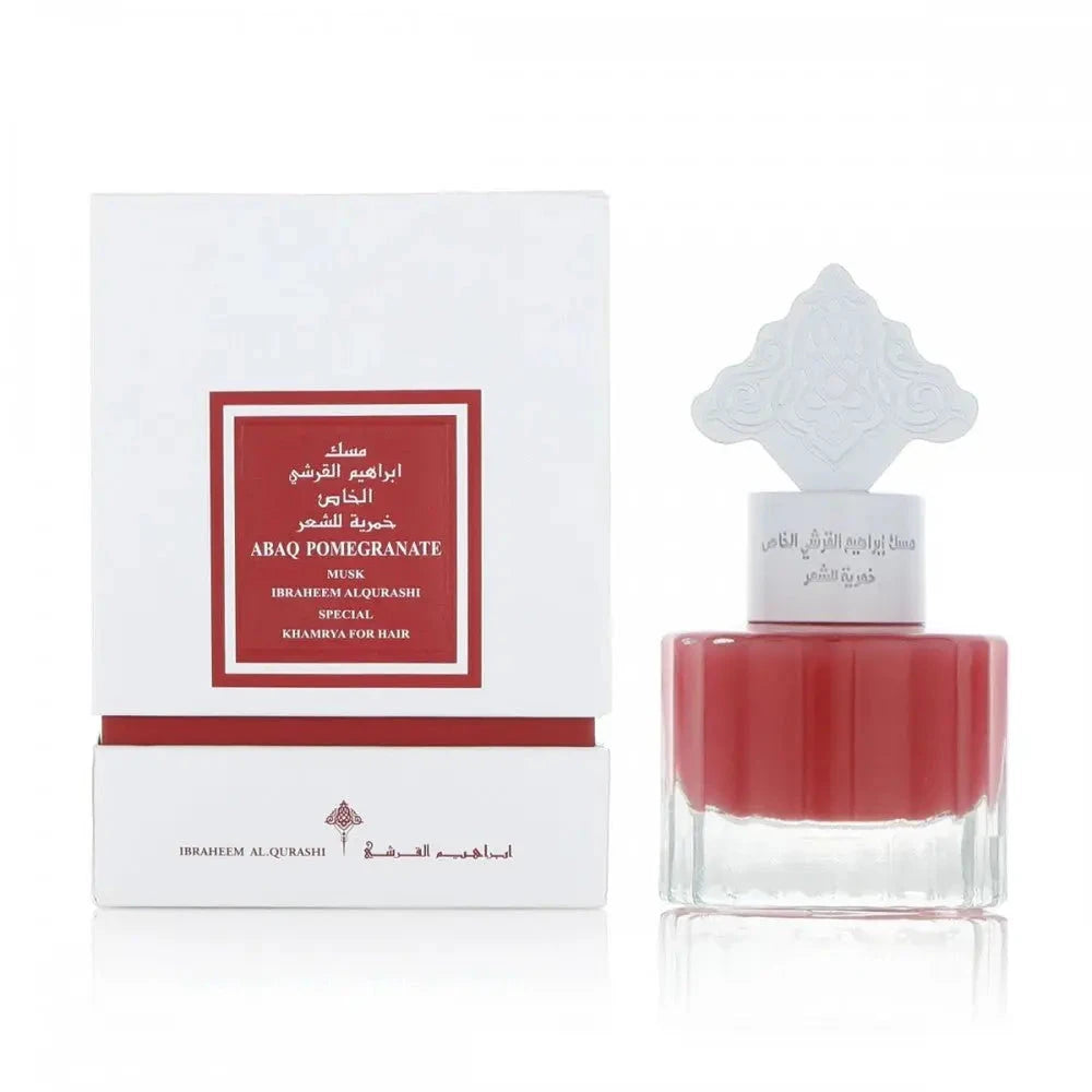 The image shows a white packaging box with a central red label for a fragrance product named "ABAQ POMEGRANATE MUSK IBRAHEEM AL.QURASHI SPECIAL KHAMRIYA FOR HAIR". Beside the box is a clear glass perfume bottle containing a red liquid, topped with a white cap featuring an intricate arabesque design. The packaging suggests that it is a special hair musk fragrance with pomegranate notes, offered by Ibraheem Al Qurashi. 
