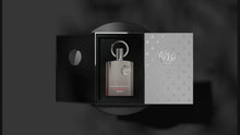 The image presents a metallic grey perfume bottle with a silver emblem, placed inside an open, elegant packaging. The left side of the packaging is black with a circular cutout revealing the bottle, while the right side has a silver finish with the bottle's emblem pattern repeated throughout. The front of the perfume bottle displays the text "SUPREMACY AFNAN" in white. The image is set against a monochromatic blurred background, highlighting the product's sophisticated design. 