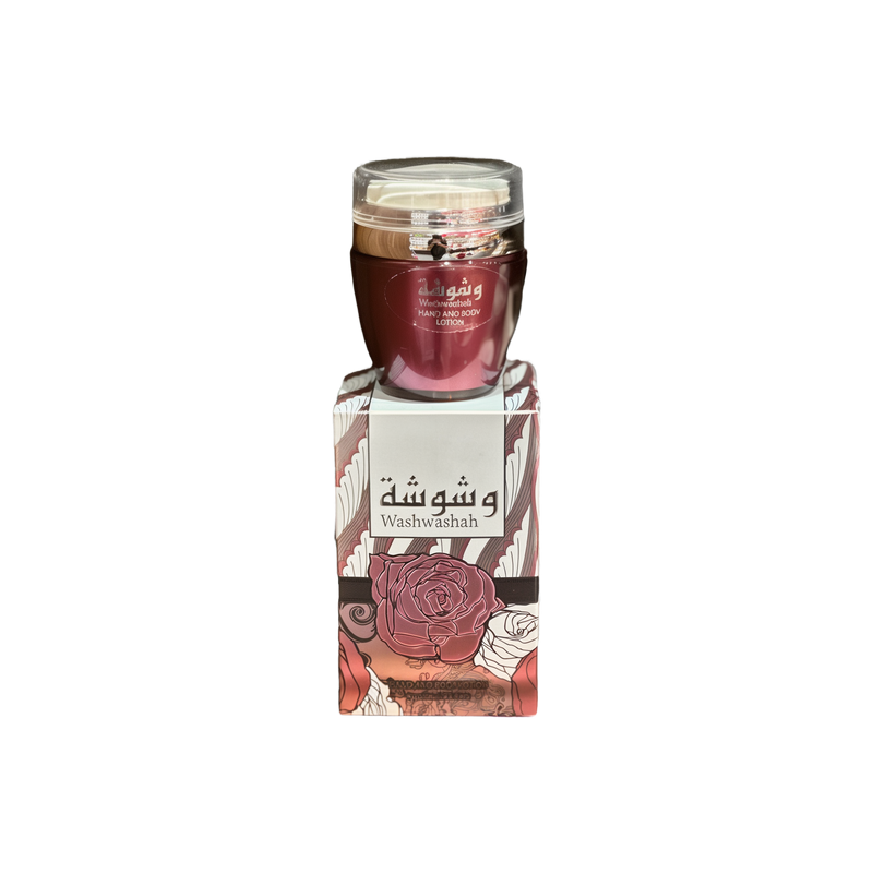 The image shows a product named "Washwashah Hand and Body Lotion." The lotion comes in a dark red container with a clear lid and is placed on top of a matching red and beige box adorned with intricate floral patterns and Arabic calligraphy. The box prominently features the product name "Washwashah" along with an illustration of a rose. The elegant and artistic packaging suggests a luxurious and high-quality skincare product.