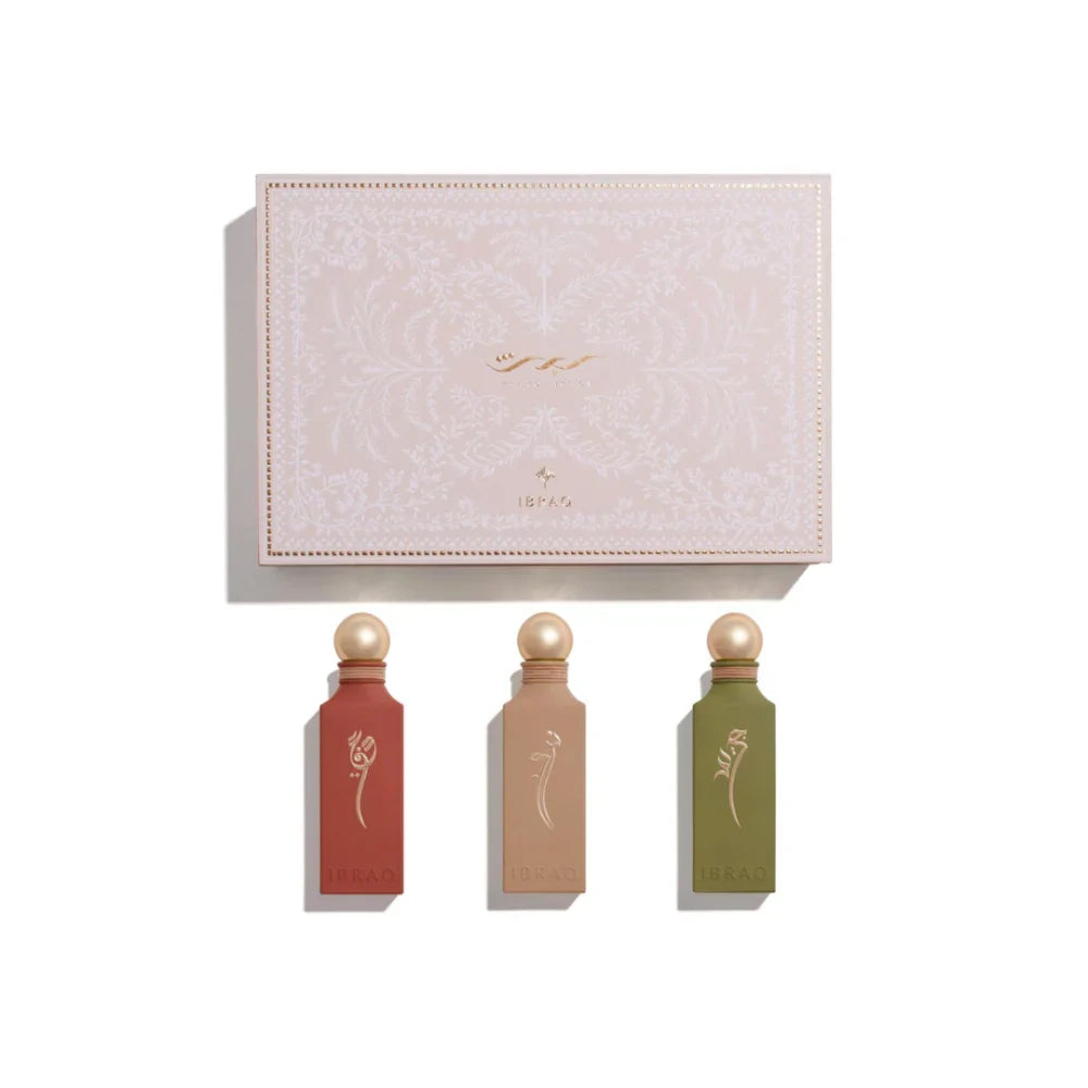Three perfume bottles with decorative caps in front of a branded box on a white background