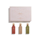 Three perfume bottles with decorative caps in front of a branded box on a white background